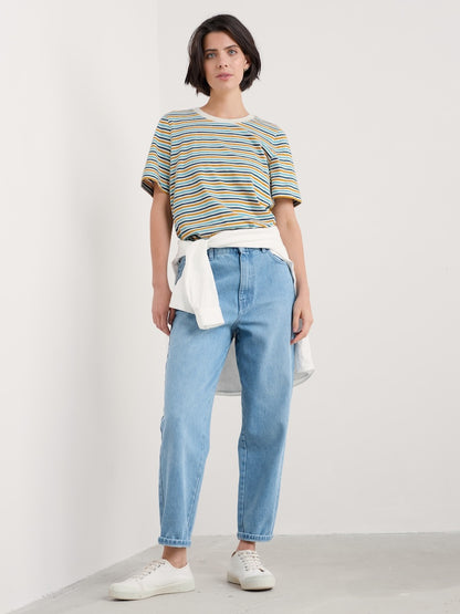 Woman wearing a striped shirt and blue jeans against a white background