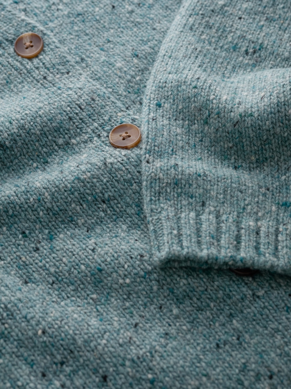 Close-up of a teal cardigan with brown buttons