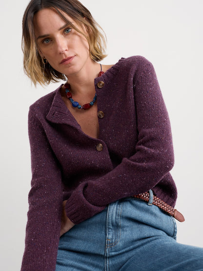 Woman wearing a purple cardigan and blue jeans against a white background