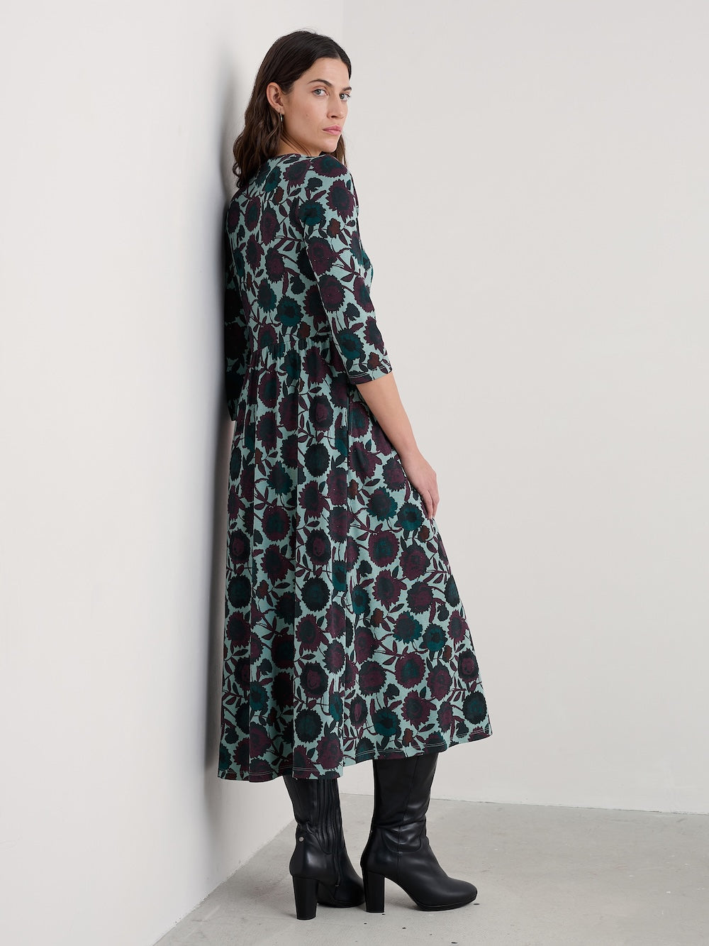Woman wearing a floral patterned dress against a white wall