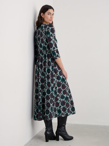 Woman wearing a floral patterned dress against a white wall