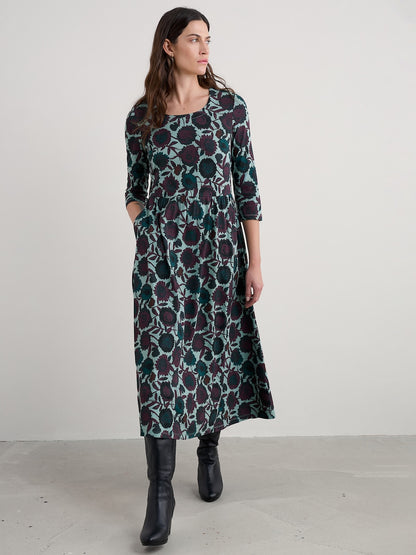 Woman wearing a long floral dress against a white background