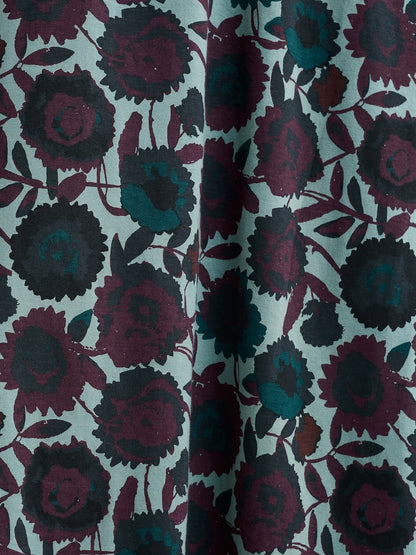 Close-up of floral patterned fabric with dark purple and black flowers on a light green background