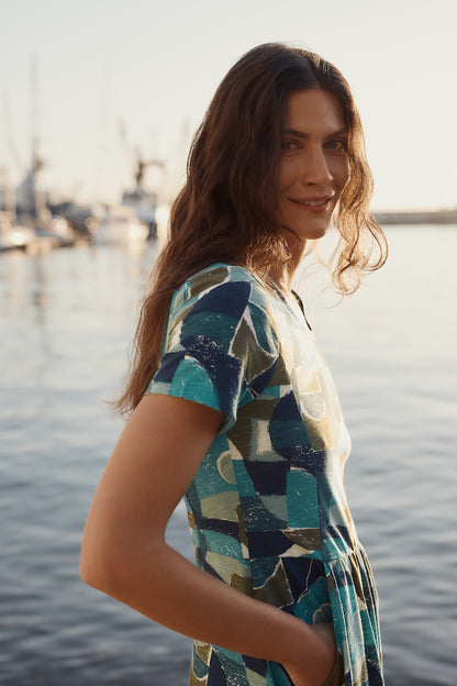 Woman wearing a patterned dress by a waterfront at sunset