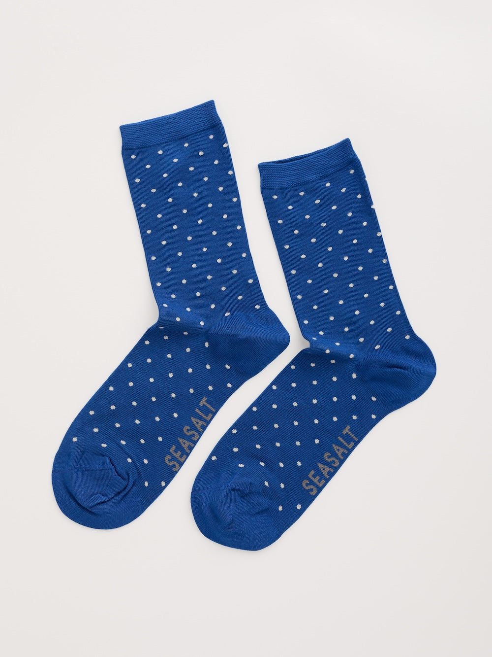 Pair of blue socks with white polka dots on a light gray background