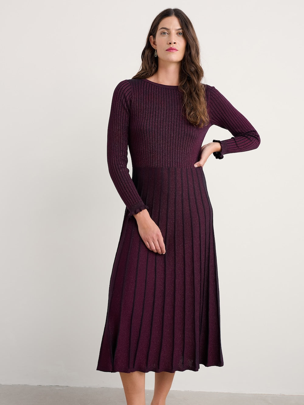 Woman wearing a long-sleeve ribbed dress against a plain background