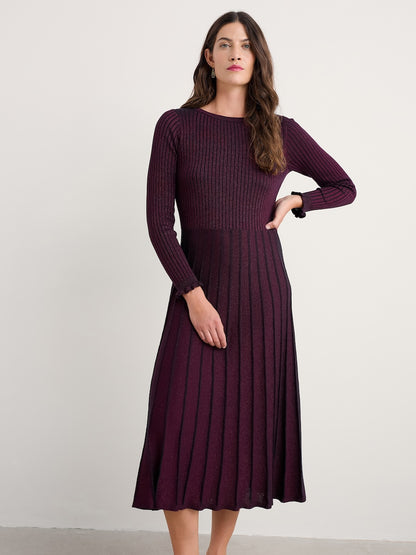 Woman wearing a long-sleeve ribbed dress against a plain background