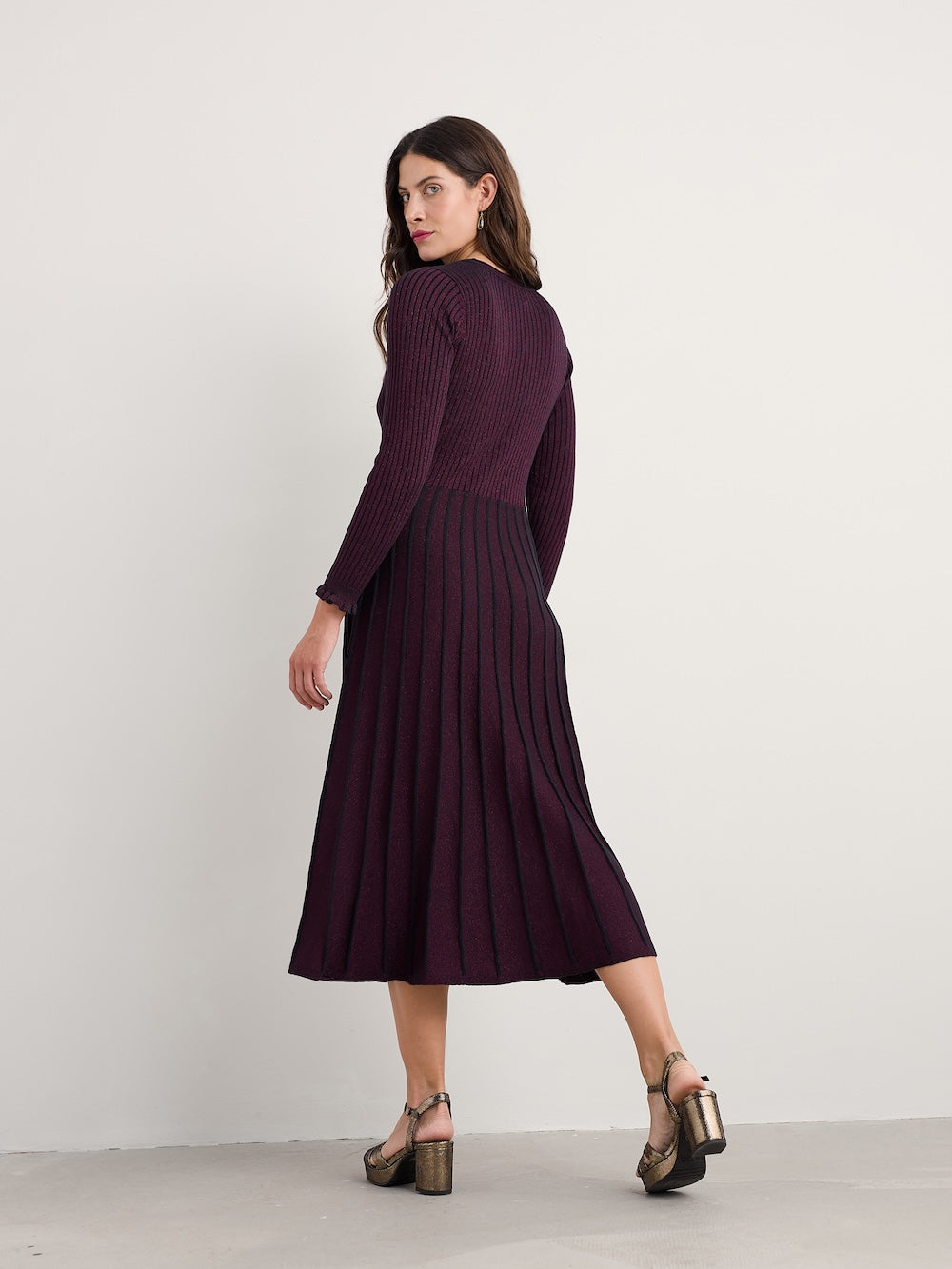 Woman wearing a long, dark purple dress against a white background