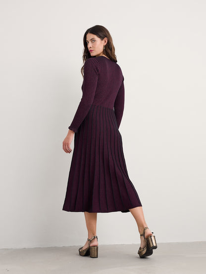 Woman wearing a long, dark purple dress against a white background