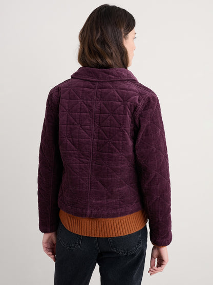 Person wearing a quilted purple jacket with a plain background