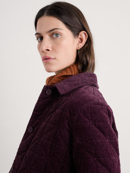 Woman wearing a purple quilted jacket with a plain background