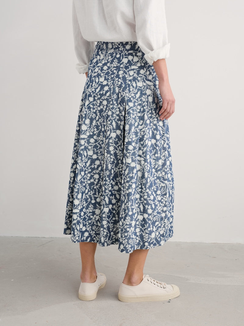 Woman wearing a blue floral skirt on a plain background