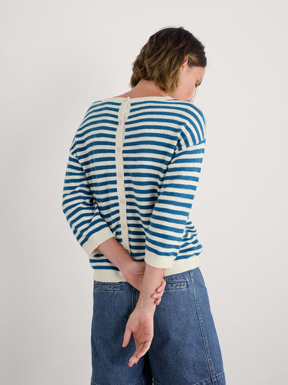 Woman wearing a blue and white striped sweater with a plain background