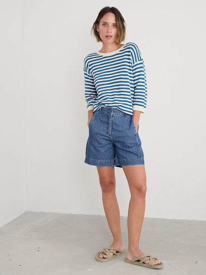 Woman wearing a striped shirt and denim shorts against a white background