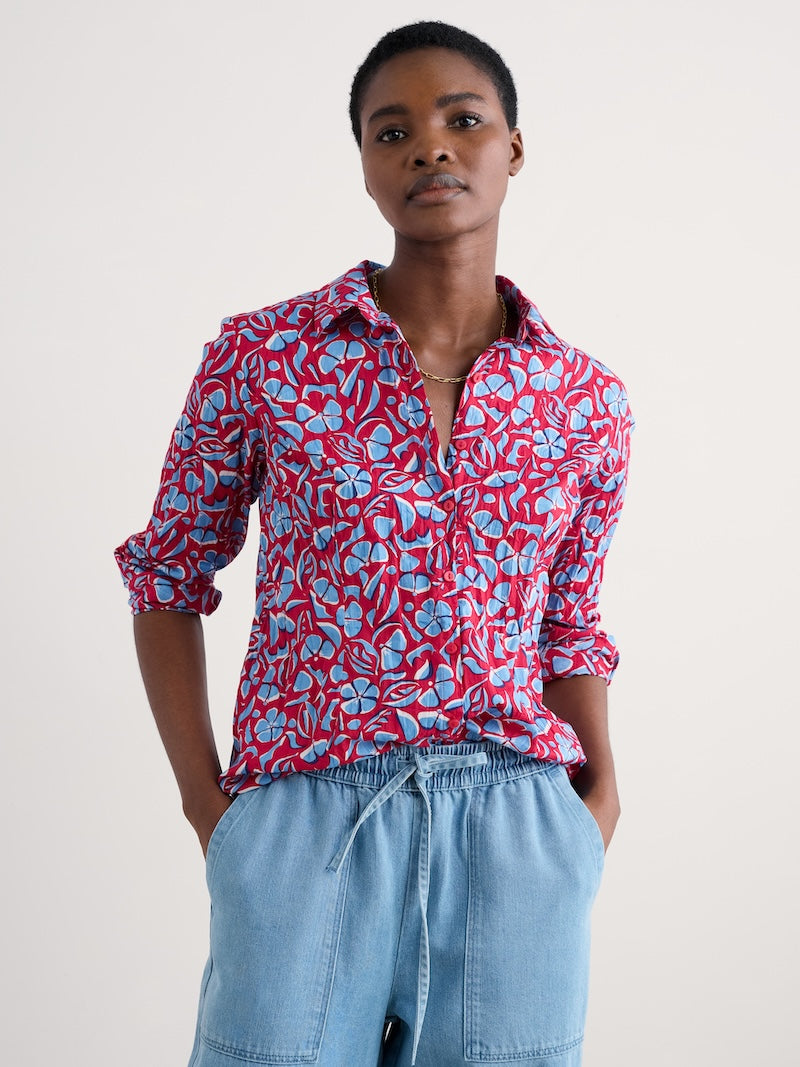Woman wearing a red floral shirt and blue jeans against a white background