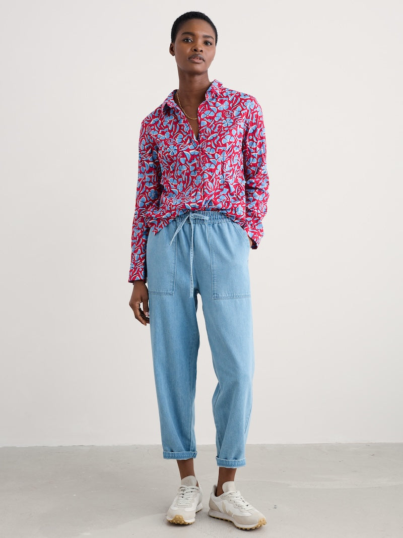 Woman wearing a colourful floral shirt and light blue jeans on a white background