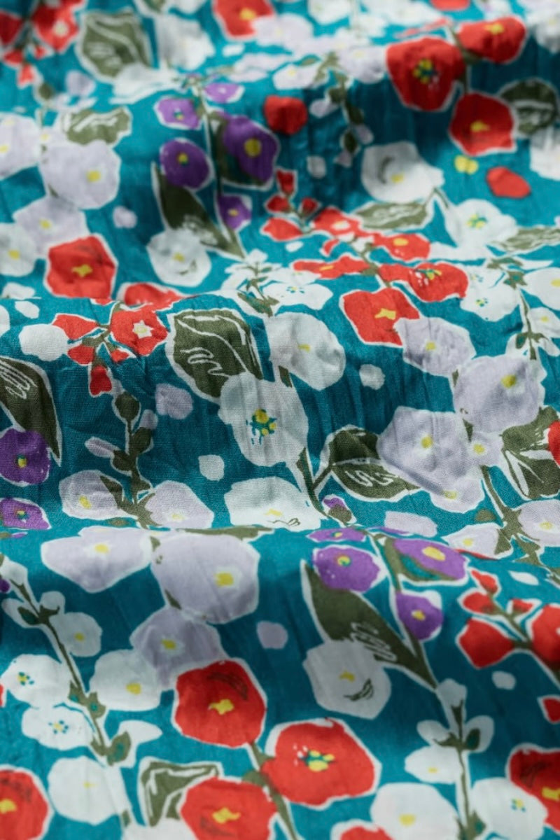 Floral fabric with red, white, and purple flowers on a blue background