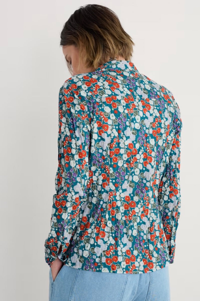 Person wearing a floral patterned shirt on a plain background