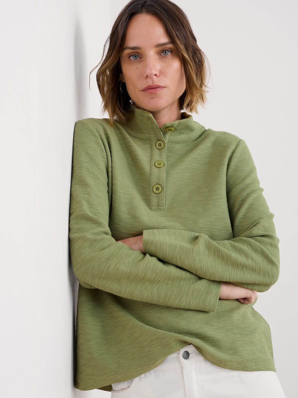 Woman wearing a green long-sleeve shirt against a white background