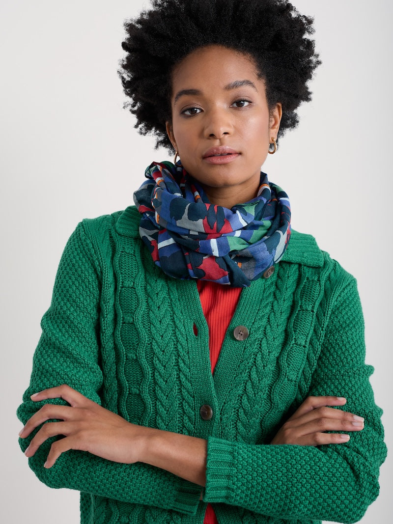 Woman wearing a green knitted cardigan and colourful scarf on a white background