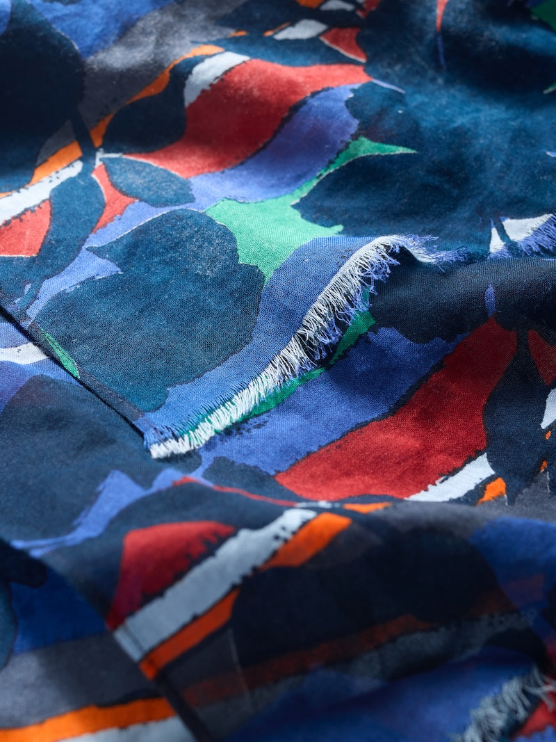 Close-up of a colorful fabric with abstract patterns in blue, red, green, and black.