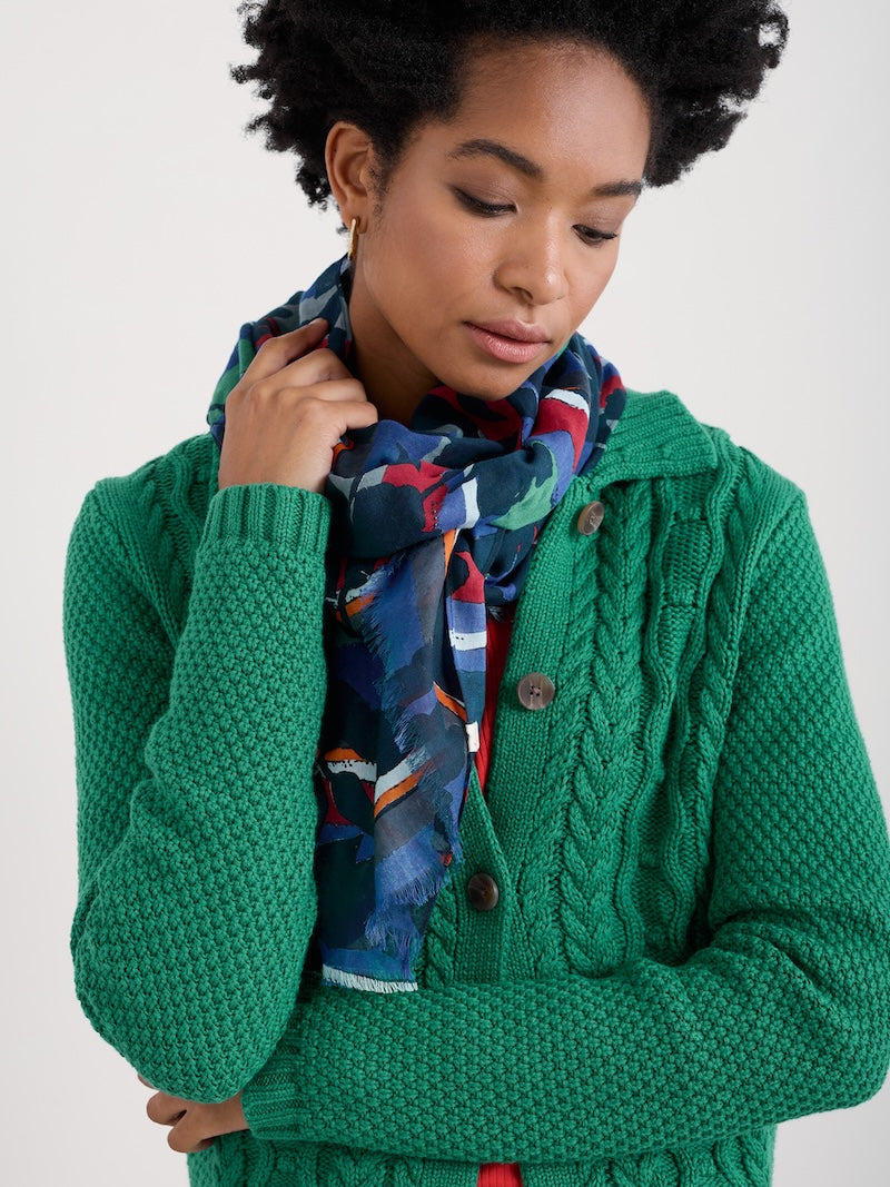 Woman wearing a green knitted cardigan with a colorful scarf on a white background