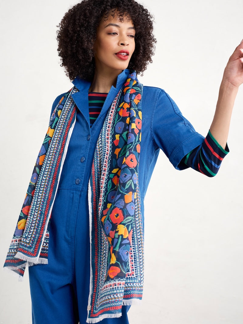 Woman wearing a blue outfit with a colourful patterned scarf on a white background