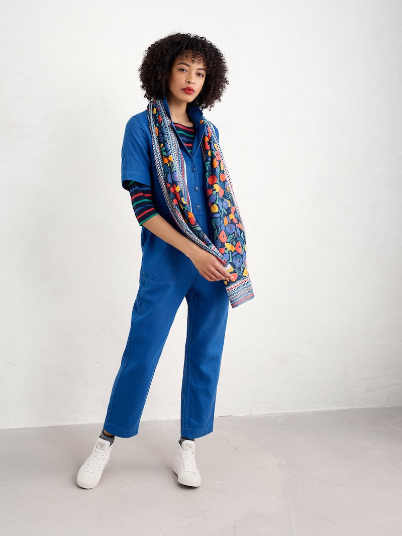 Person wearing a blue outfit with a colourful scarf on a white background