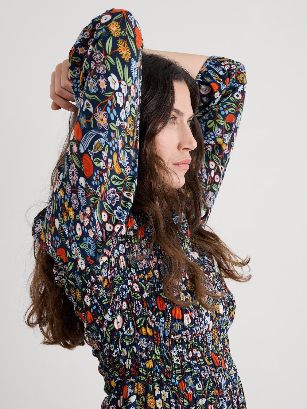 Woman wearing a colorful floral dress with a hood against a white background