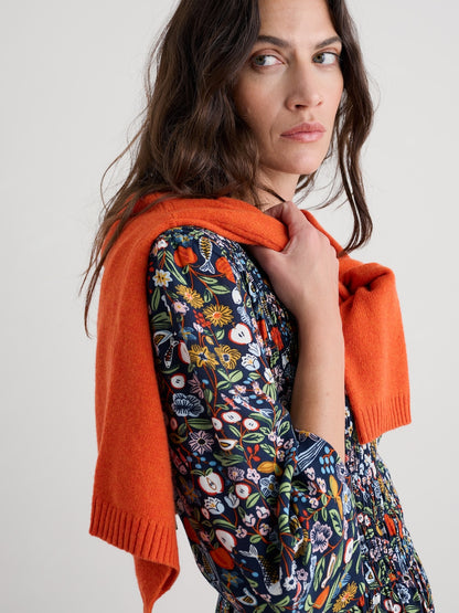 Woman wearing a floral dress with an orange cardigan on a white background