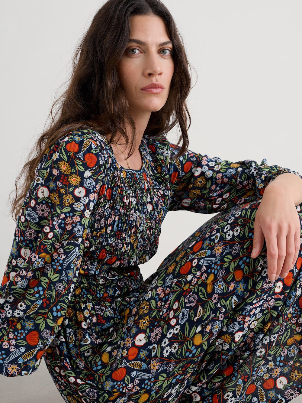 Woman wearing a floral dress sitting on a white surface