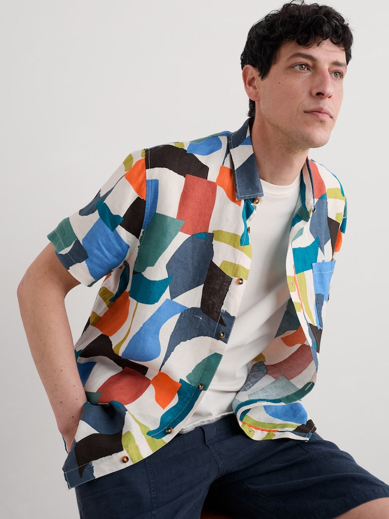 Man wearing a colourful geometric patterned shirt against a plain background
