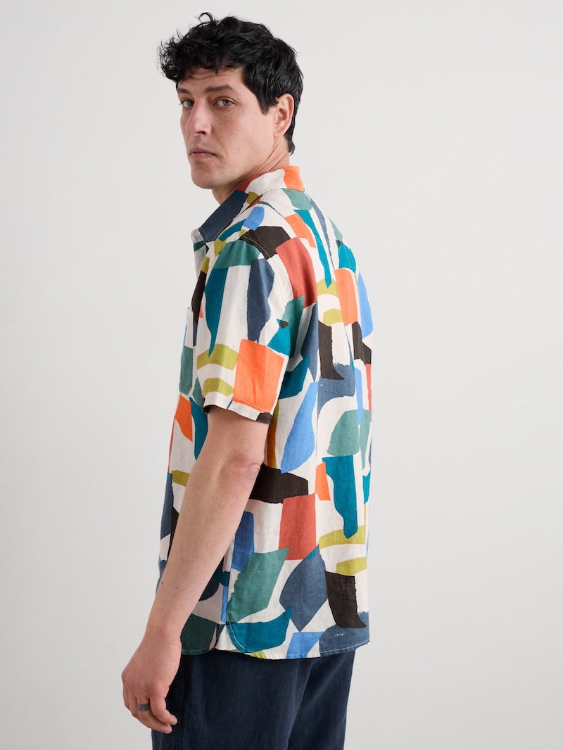 Man wearing a colourful geometric patterned shirt against a plain background