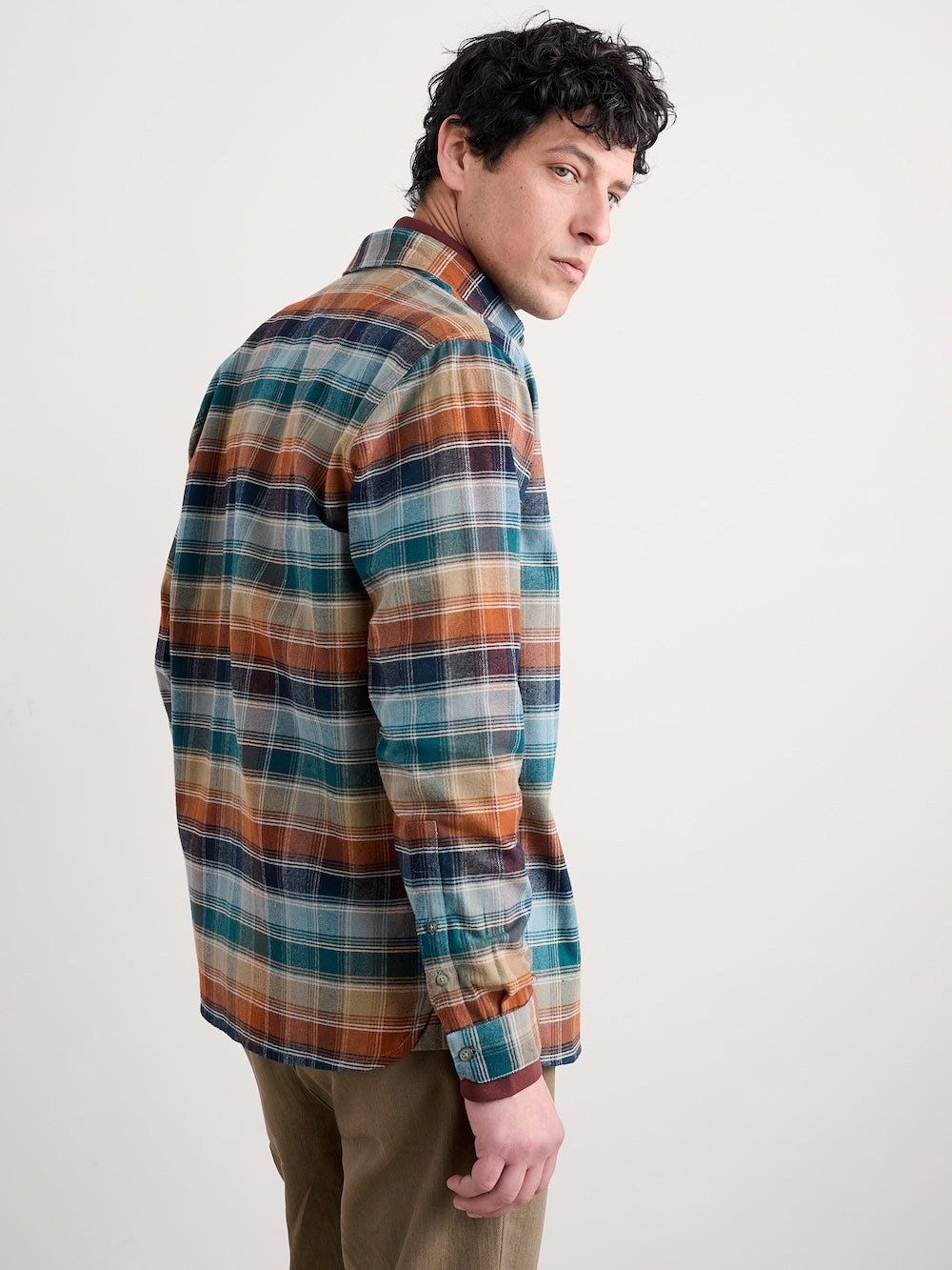 Man wearing a plaid shirt with a neutral background