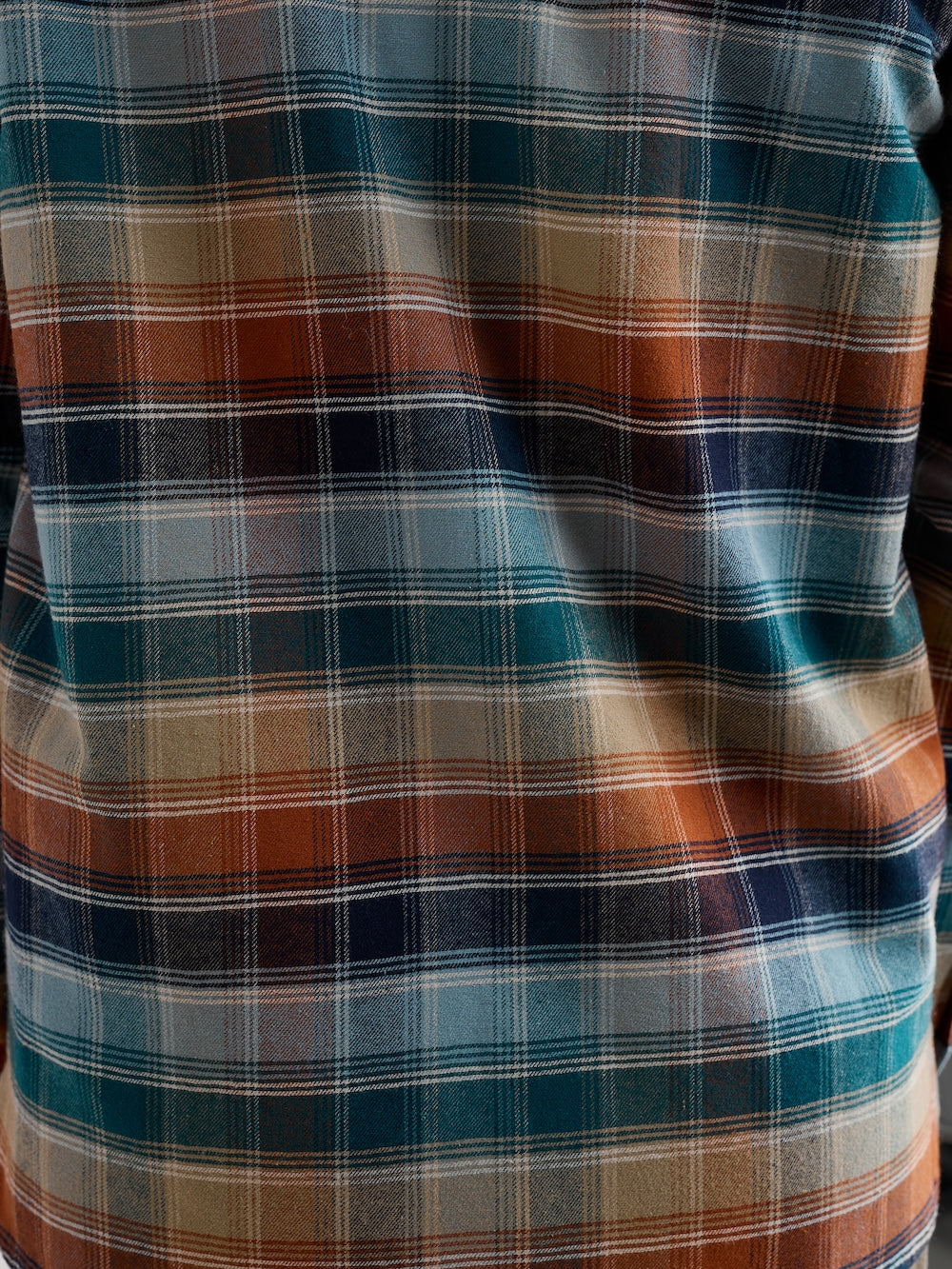 Close-up of a plaid shirt with blue, brown, and beige colors.