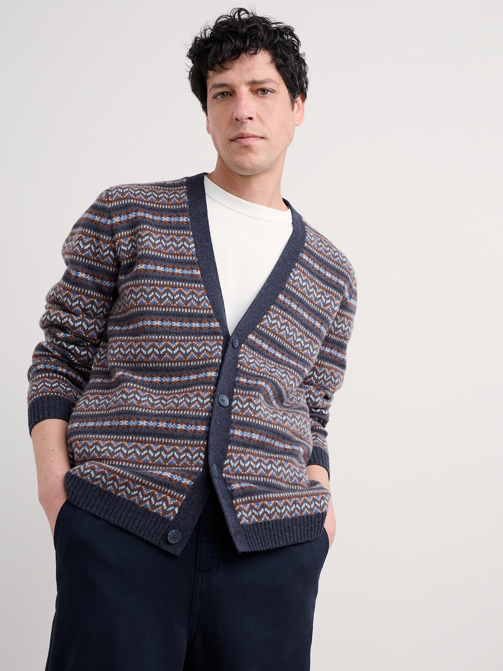 Man wearing a patterned cardigan on a plain background