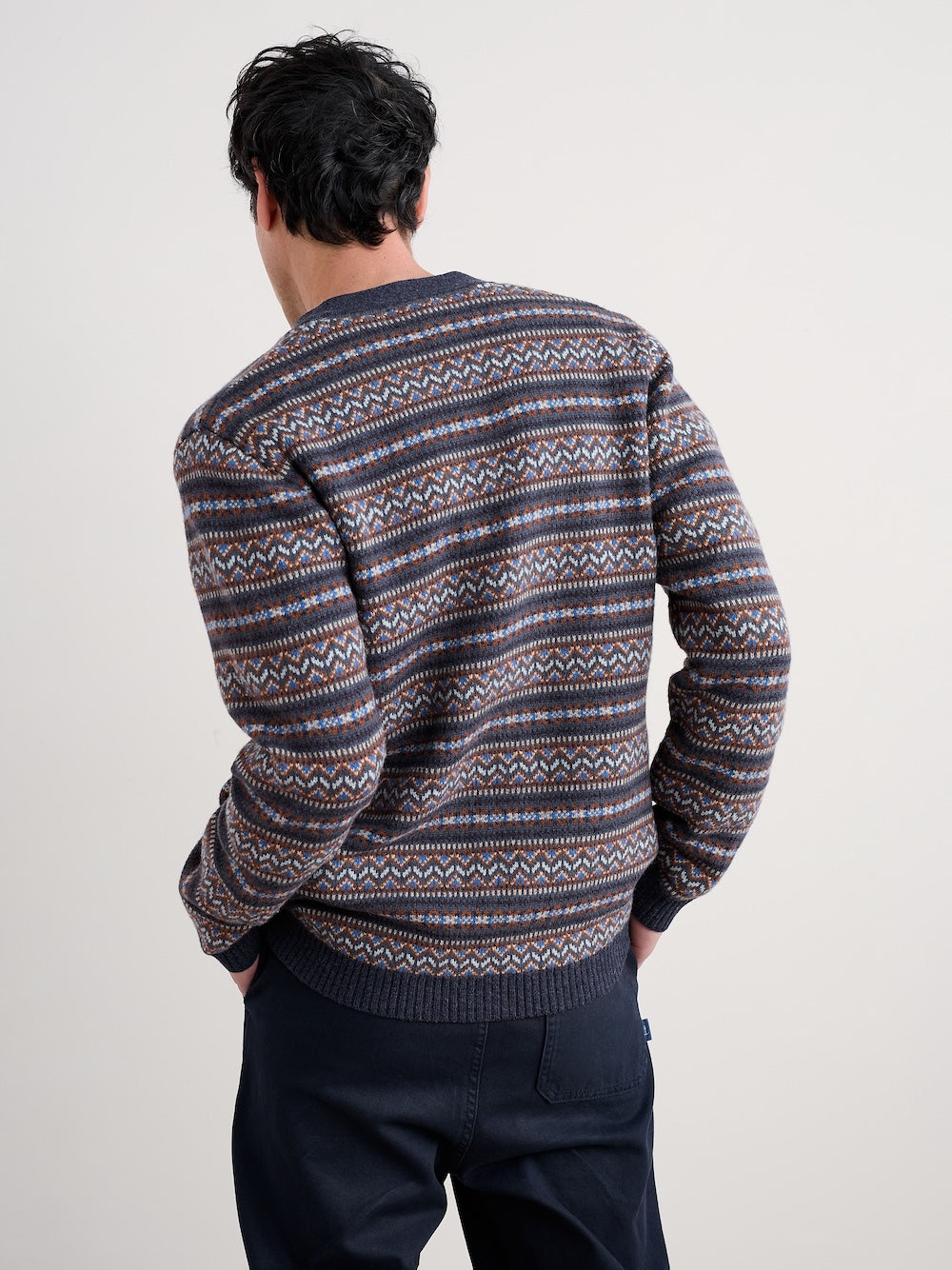 Man wearing a patterned cardigan against a plain background