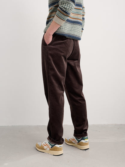 Person wearing brown pants and a patterned sweater against a white background