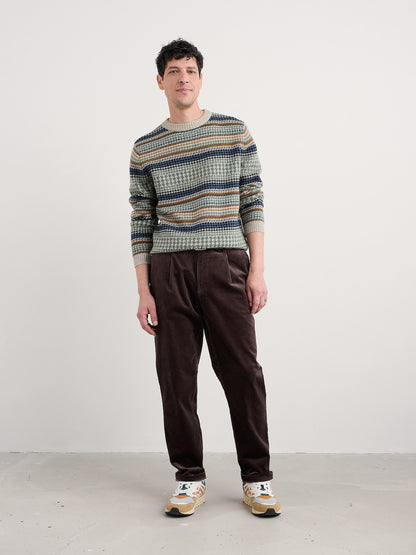 Man wearing a striped sweater and brown pants on a white background