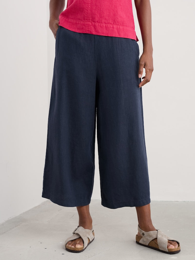 Person wearing navy wide-leg pants and a pink top on a white background