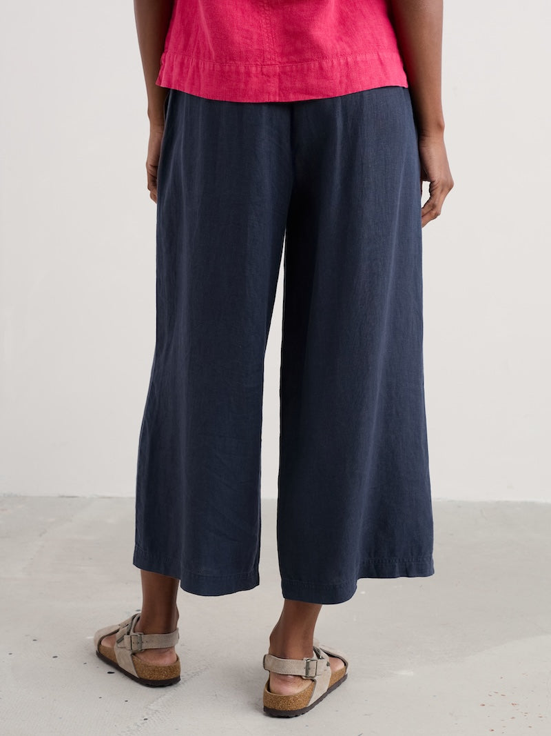 Woman wearing navy wide-leg pants and a pink top on a white background