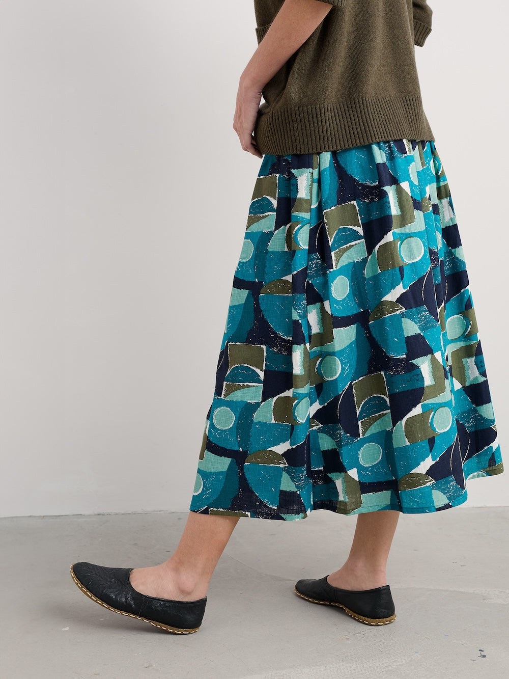Person wearing a patterned skirt with geometric shapes on a plain background