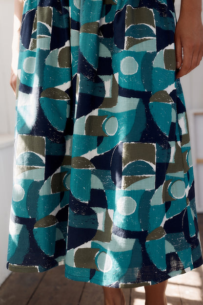 Person wearing a dress with a geometric pattern in blue, green, and gray.