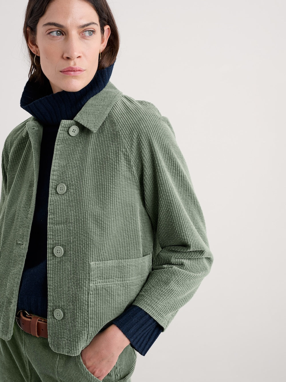 Woman wearing a green corduroy jacket on a plain background