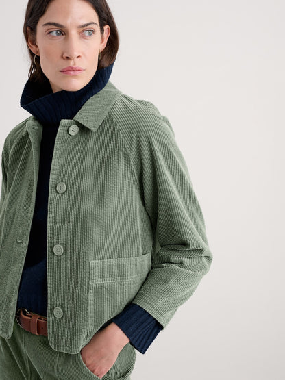 Woman wearing a green corduroy jacket on a plain background