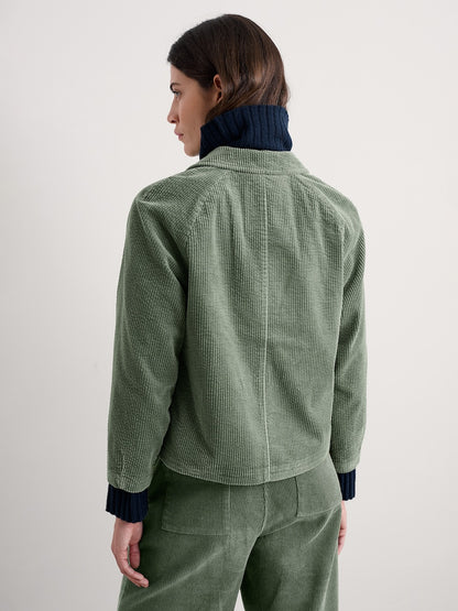 Person wearing a green cord jacket and pants on a white background