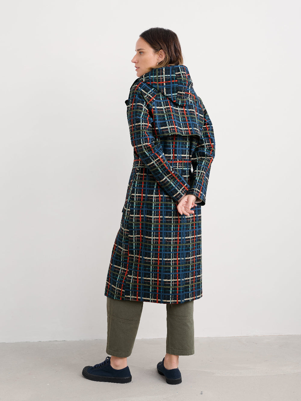 Person wearing a plaid rain coat standing against a white background