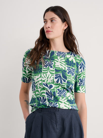 Woman wearing a green and blue patterned shirt against a plain background