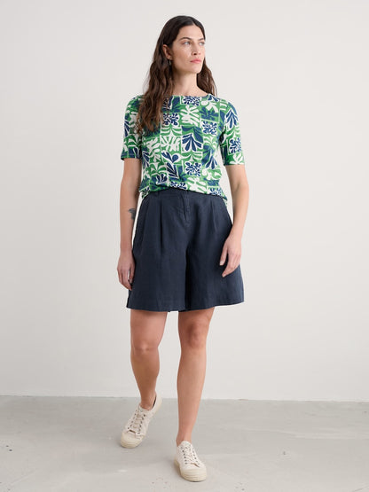 Woman wearing a patterned top and navy skirt on a white background