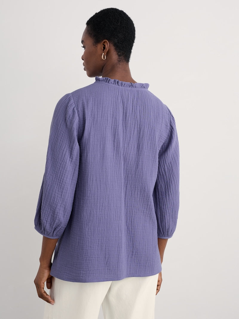 Woman wearing a purple textured blouse against a plain background